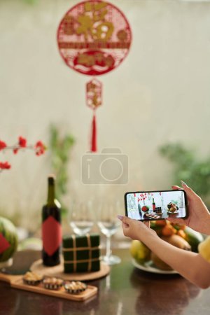 Téléchargez les photos : Mains de femme photographiant la nourriture qu'elle a préparée pour la célébration du Nouvel An chinois - en image libre de droit