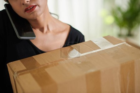 Photo for Cropped image of woman holding big cardboard box when calling to moving company - Royalty Free Image