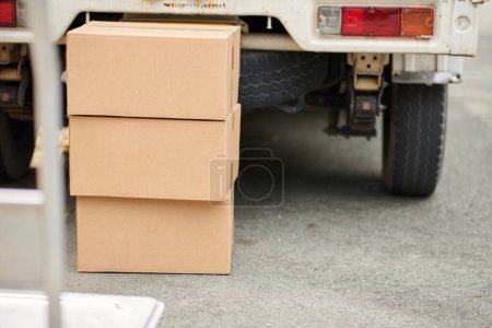 Téléchargez les photos : Cardboard boxes with personal belongings at truck of movers - en image libre de droit