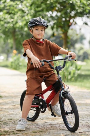 Téléchargez les photos : Portrait of preteen boy wearing protective helmet when riding bicycle in park - en image libre de droit