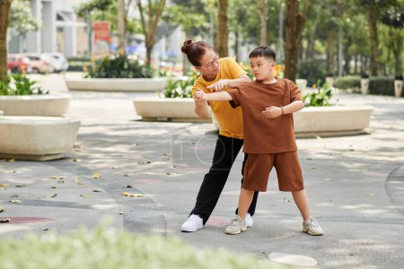 Téléchargez les photos : Senior femme enseignant exercice garçon préadolescent quand ils travaillent dans le parc - en image libre de droit