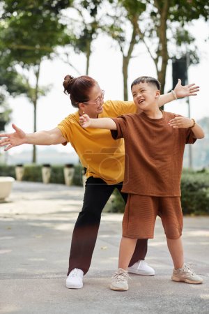 Téléchargez les photos : Joyful preteen boy spending time with grandmother exercising in park - en image libre de droit