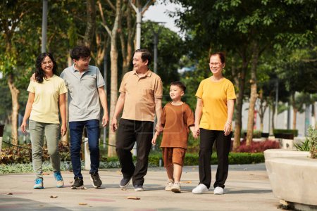 Téléchargez les photos : Famille passant du temps ensemble à marcher dans un parc ensoleillé le dimanche matin - en image libre de droit