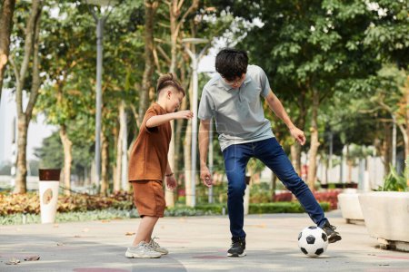 Téléchargez les photos : Joyful father and son playing soccer in park - en image libre de droit