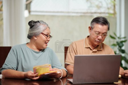 Téléchargez les photos : Couple aîné payer des factures en ligne via le site - en image libre de droit