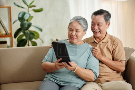 Téléchargez les photos : Happy senior couple video calling their adult children or grandchildren - en image libre de droit