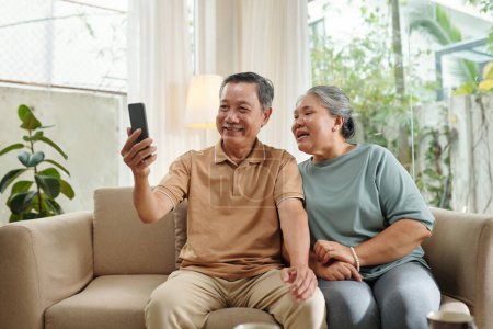 Téléchargez les photos : Happy senior couple video calling grandchildren to discuss news - en image libre de droit