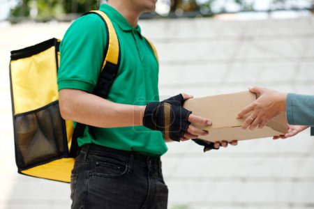 Téléchargez les photos : Courier with big backpack delivering package with food to customer - en image libre de droit