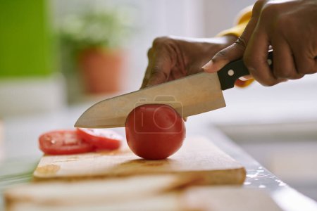 Photo for Woman cutting fresh tomatoes in thin slices when cooking dinner - Royalty Free Image