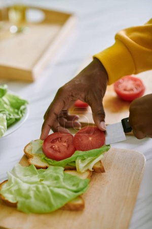 Photo for Woman putting thin tomato slices on lettuce when making sandwich - Royalty Free Image