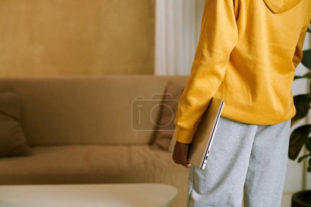 Foto de Imagen recortada de la chica en ropa de casa que lleva el ordenador portátil al sofá - Imagen libre de derechos