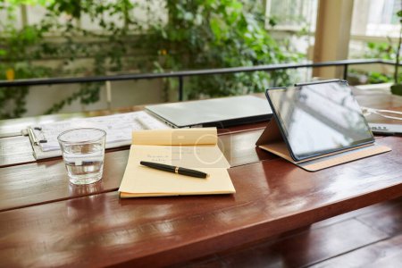 Foto de Planificador con nota junto a tableta digital en mesa de madera en cafetería - Imagen libre de derechos