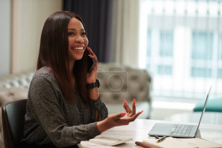 Photo for Portrait of smiling female entrepreneur discussing project on phone with colleague - Royalty Free Image