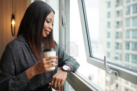 Photo for Smiling elegant businesswoman enjoying view from her apartment in skyscraper - Royalty Free Image