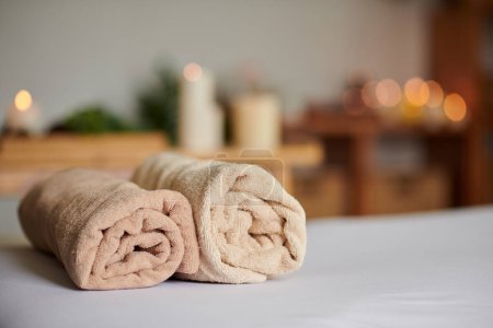 Photo for Two rolled up soft towels on bed in spa salon - Royalty Free Image