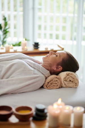 Photo for Woman in bathrobe resting on bed in beauty salon after getting relaxing spa procedure - Royalty Free Image