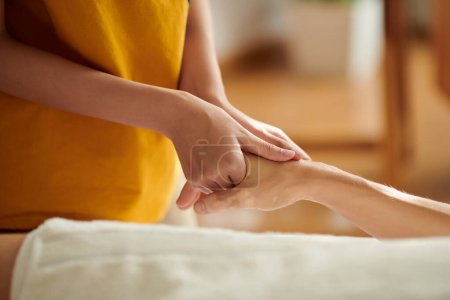 Photo for Masseuse massaging hands of woman using smooth gentle strokes - Royalty Free Image