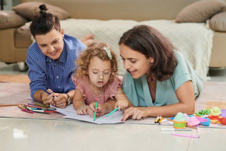 Téléchargez les photos : Joyful lesbian couple and their little daughter coloring pictures together - en image libre de droit