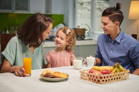 Téléchargez les photos : Joyful family of three eating healthy breakfast at home - en image libre de droit