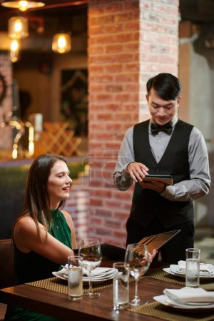 Téléchargez les photos : Smiling elegant woman ordering food at restaurant - en image libre de droit