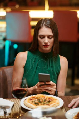 Téléchargez les photos : Portrait de jeune femme élégante prenant une photo de pizza avant de manger - en image libre de droit