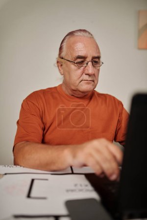 Photo for Portrait of aged man checking specifications on computer when working on construction plan of house - Royalty Free Image