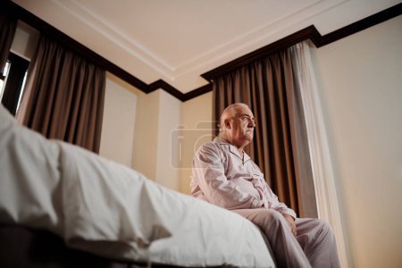 Téléchargez les photos : Aged man suffering from depression sitting on bed after waking up - en image libre de droit