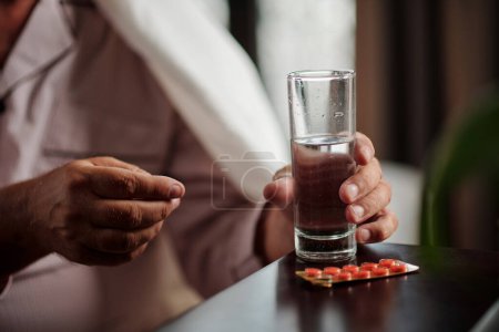 Photo for Hands of sick senior man taking pills and drinking water - Royalty Free Image