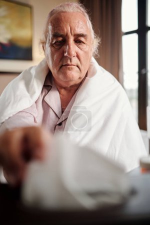 Foto de Hombre anciano enfermo tomando papel para sonarse la nariz - Imagen libre de derechos