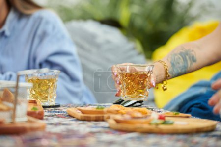 Téléchargez les photos : Personne prenant verre avec boisson de la table lorsque vous traînez avec des amis - en image libre de droit