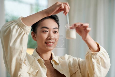 Foto de Mujer sonriente mezclando base de jabón derretido con aceite esencial - Imagen libre de derechos