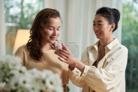 Foto de Mujer sonriente pidiendo a un amigo que huela jabón derretido pased mezclado con aceite esencial - Imagen libre de derechos