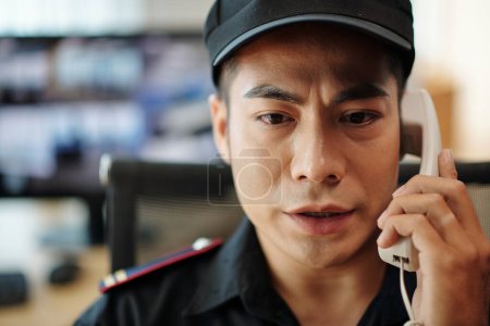 Photo for Portrait of serious operator talking on phone after noticing suspicious activity on screen - Royalty Free Image