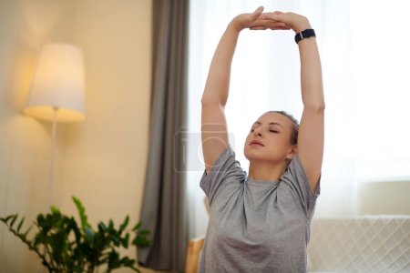 Photo for Woman raising arms above head and doing breathing exercise - Royalty Free Image