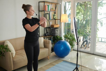 Photo for Fitness blogger streaming herself working out at home - Royalty Free Image