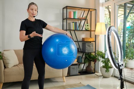 Foto de Fitness blogger explaining subscribers how to exercise with fitness ball at home - Imagen libre de derechos