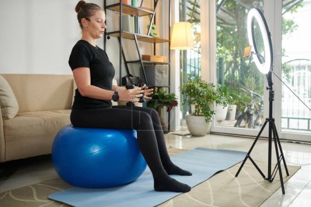 Téléchargez les photos : Online fitness trainer working out with dumbbells in front of camera - en image libre de droit