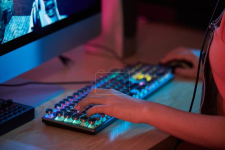 Foto de Imagen de primer plano de una adolescente jugando videojuegos con un potente ordenador y un teclado rgb - Imagen libre de derechos