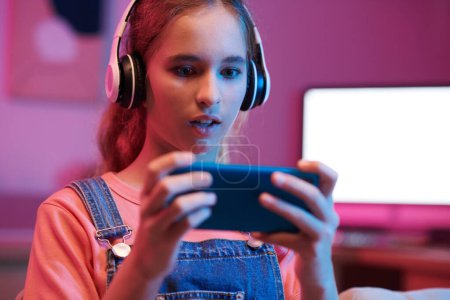 Téléchargez les photos : Portrait of amazed teenage girl playing game on smarphone - en image libre de droit