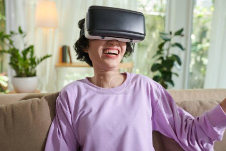 Téléchargez les photos : Joyful girl watching movie in virtual reality headset - en image libre de droit