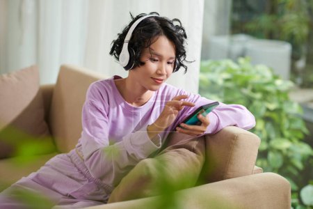 Téléchargez les photos : Adolescente écoutant de la musique dans des écouteurs et des amis textos - en image libre de droit