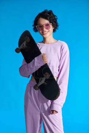 Foto de Portrait of happy teenage girl holding skateboard - Imagen libre de derechos