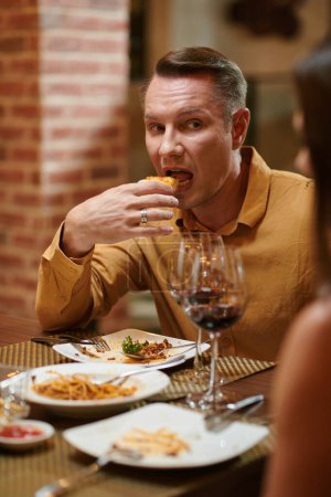 Foto de Retrato del hombre mordiendo rebanada de pizza cuando escucha a su novia hablando - Imagen libre de derechos