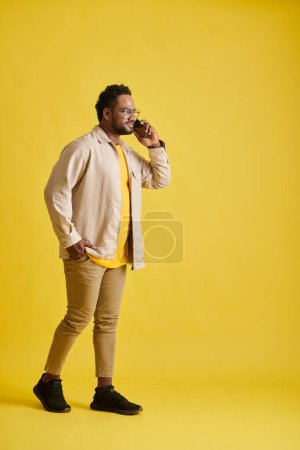 Photo for Positive man walking and talking on phone, isolated on yellow - Royalty Free Image