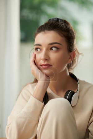 Foto de Portrait of melancholic young woman pondering over ideas after listening to music at home - Imagen libre de derechos