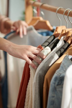 Photo for Cropped image of woman choosing clothes in closet when deciding what to wear - Royalty Free Image
