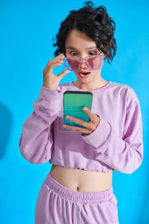 Foto de Teenage girl reading shocking news on smartphone - Imagen libre de derechos