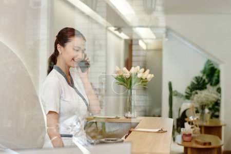 Téléchargez les photos : Spa salon receptionist worker talking on phone with client - en image libre de droit