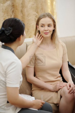 Photo for Cosmetoloigst checking skin of young woman visiting spa salon - Royalty Free Image