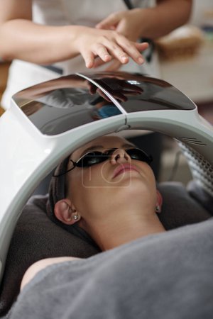 Photo for Young woman getting skin rejuvenation LED light facial treatment - Royalty Free Image